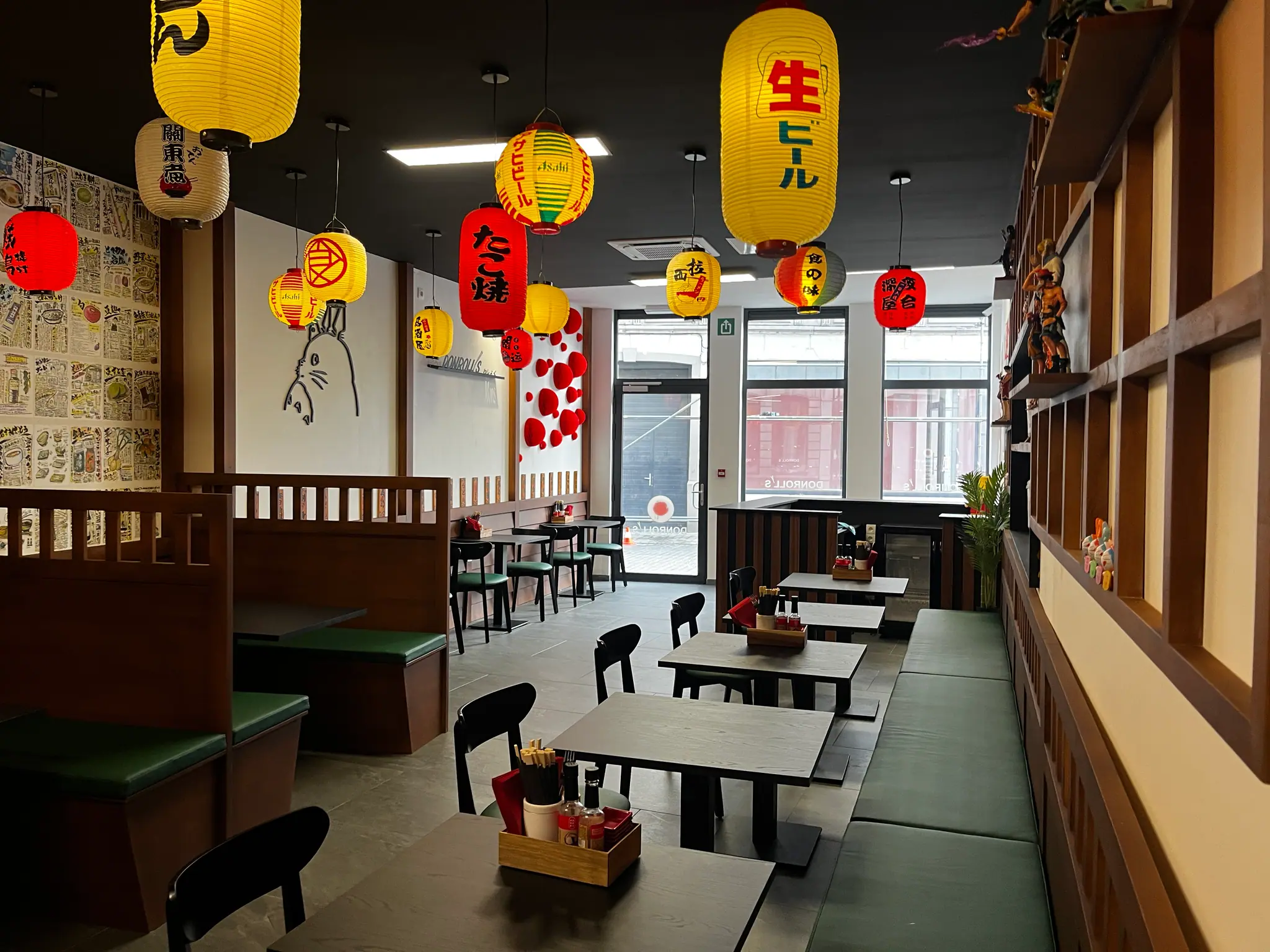 Une salle de restaurant agencée en bois : banquettes, claustras à tasseaux, panneaux muraux et lanternes suspendues