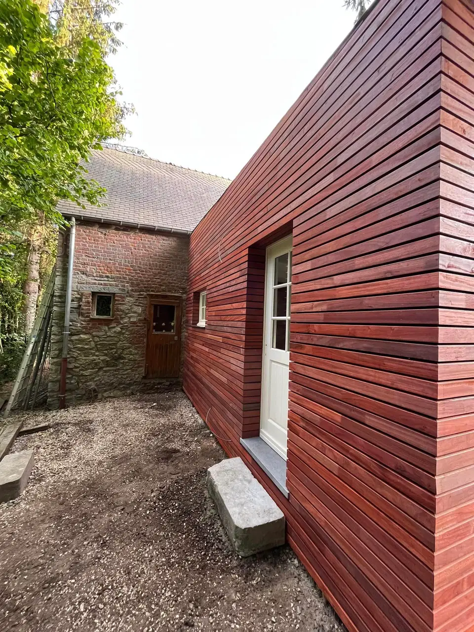 Une annexe de pierre habillée de clins horizontaux — vers la fin du chantier