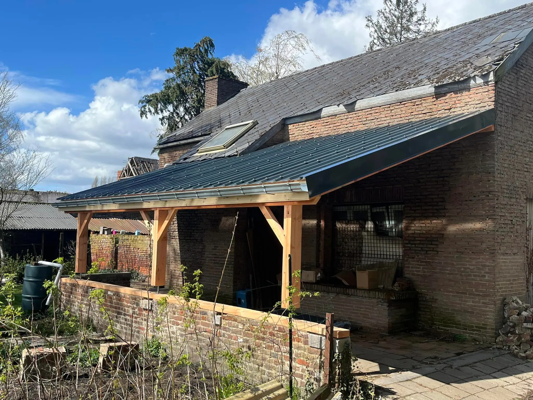 Le carport terminé contre la ferme de brique, couverture à joint debout posée