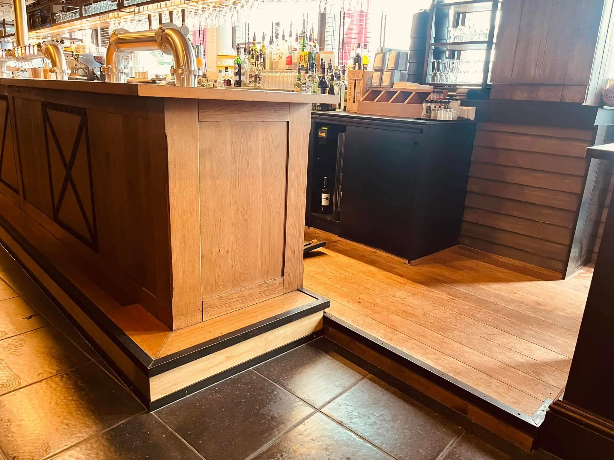 Comptoir de brasserie en bois massif à façade à panneaux, tireuses et bouteilles à l’arrière-plan
