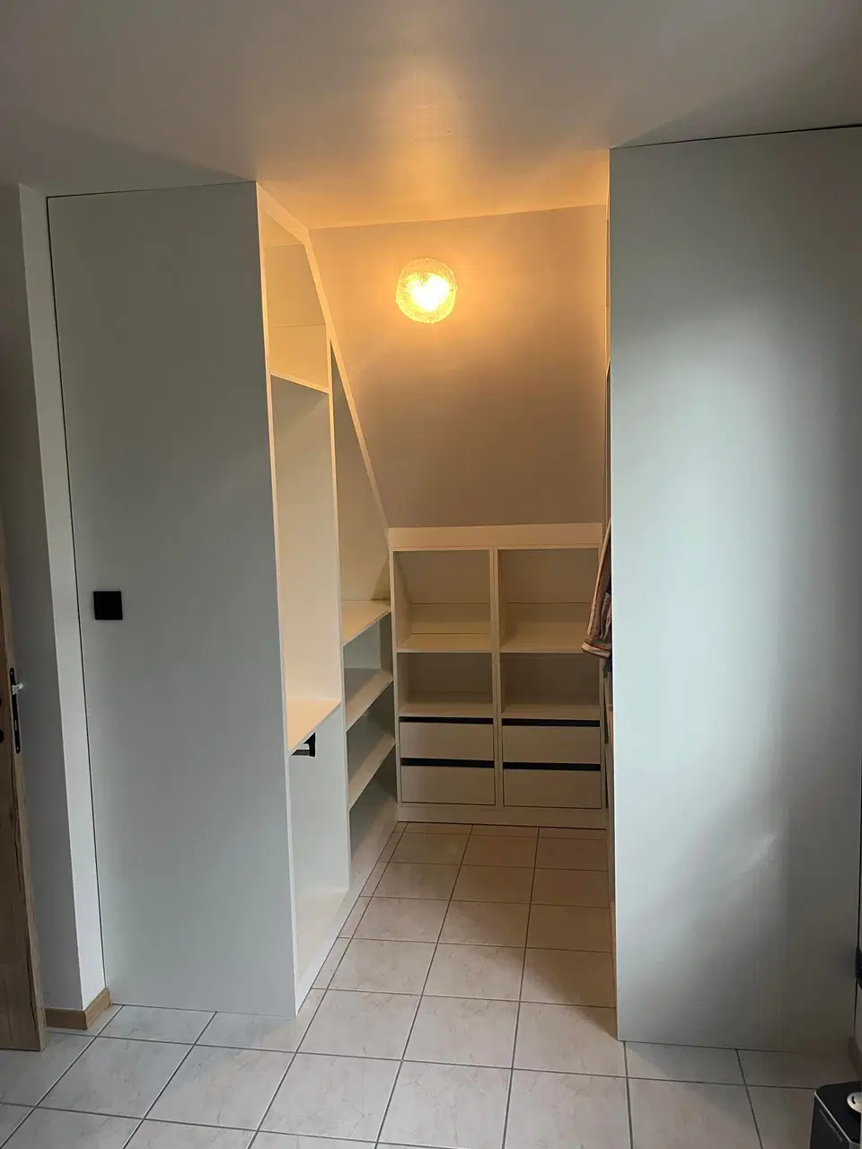 Un dressing ouvert sous comble, éclairé au plafond — en fin de chantier