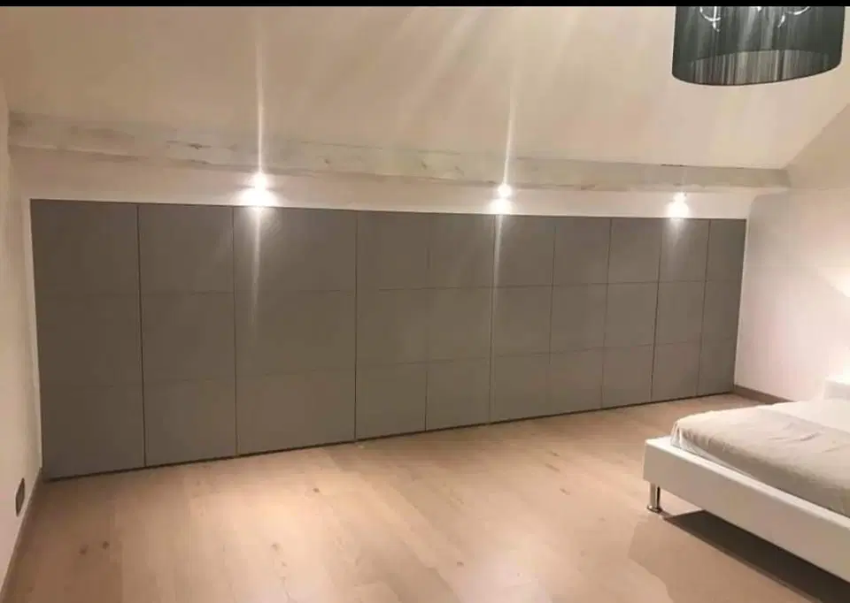 Un dressing sous comble, façades blanches et casiers — pendant les travaux
