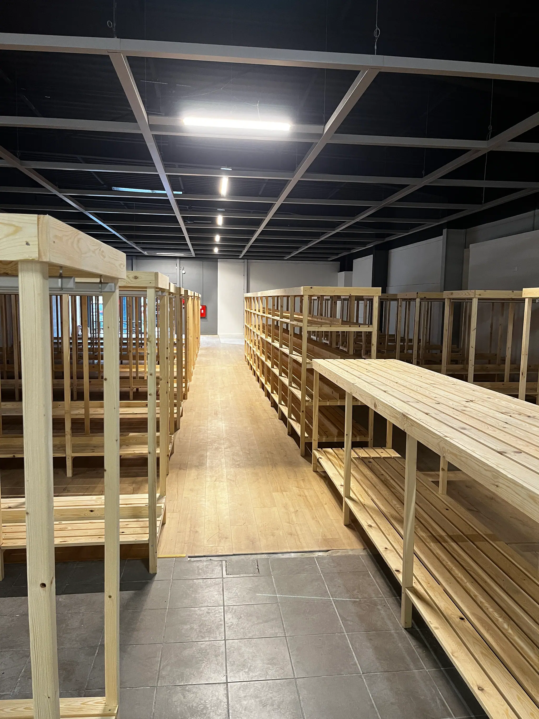 Des rangées d’étagères et une table de présentation en bois massif, montées dans une surface commerciale vide