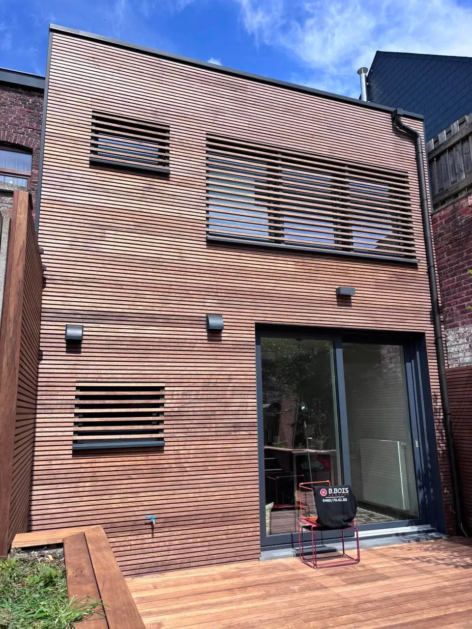 Le volume de trois quarts, la terrasse en bois dur courant au pied de la façade