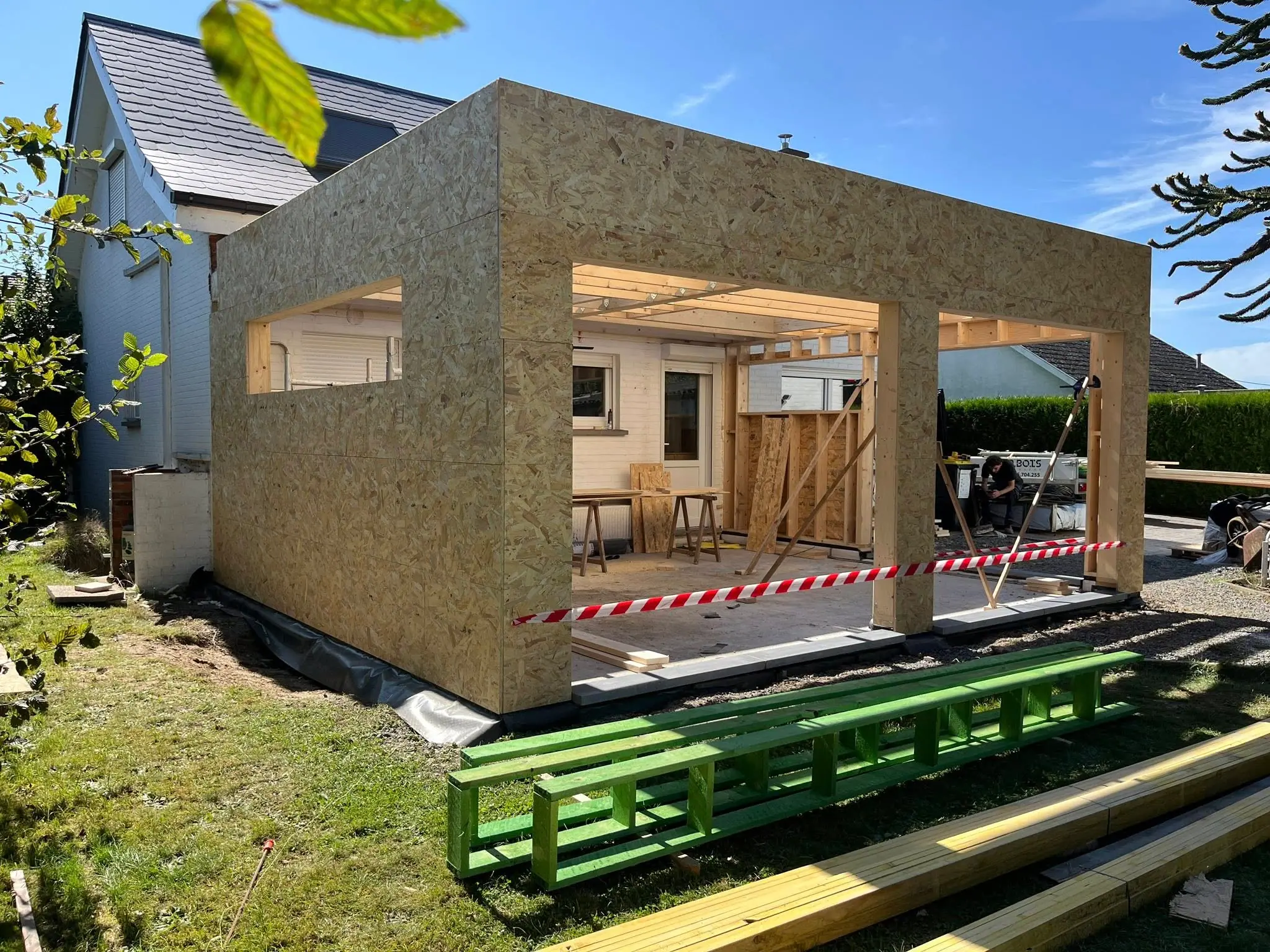 Le caisson en OSB levé sur la dalle, engin de chantier et rubalise