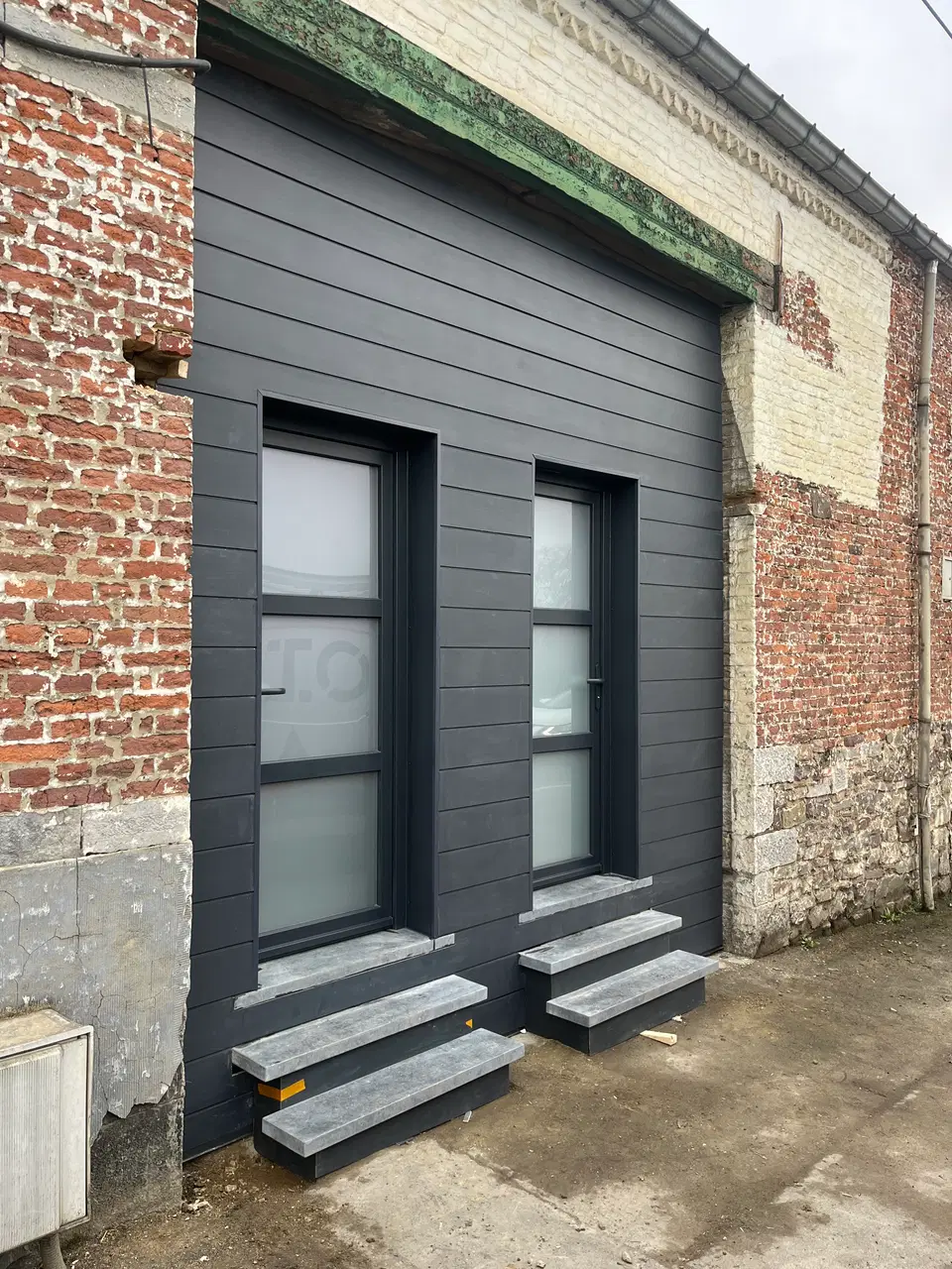 Une façade de bâti ancien rhabillée en fibres-ciment — pendant les travaux