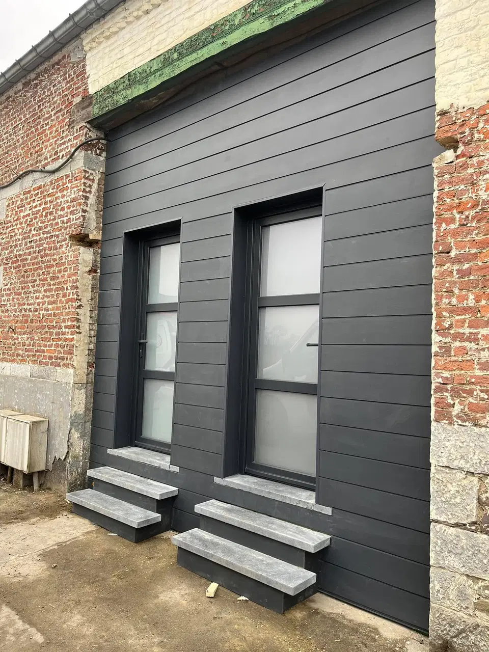 Une façade de bâti ancien rhabillée en fibres-ciment — vers la fin du chantier