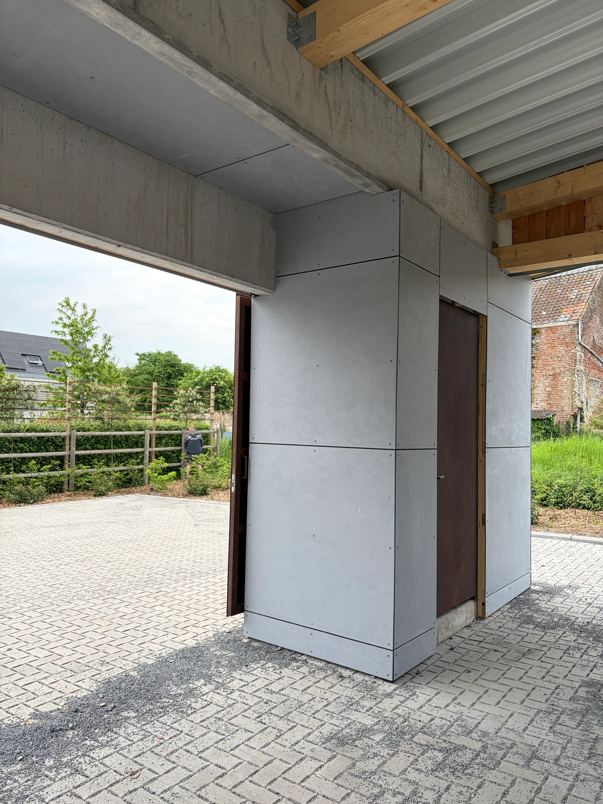 Le détail d’un angle : panneau de béton, porte coulissante en acier corten et pavage
