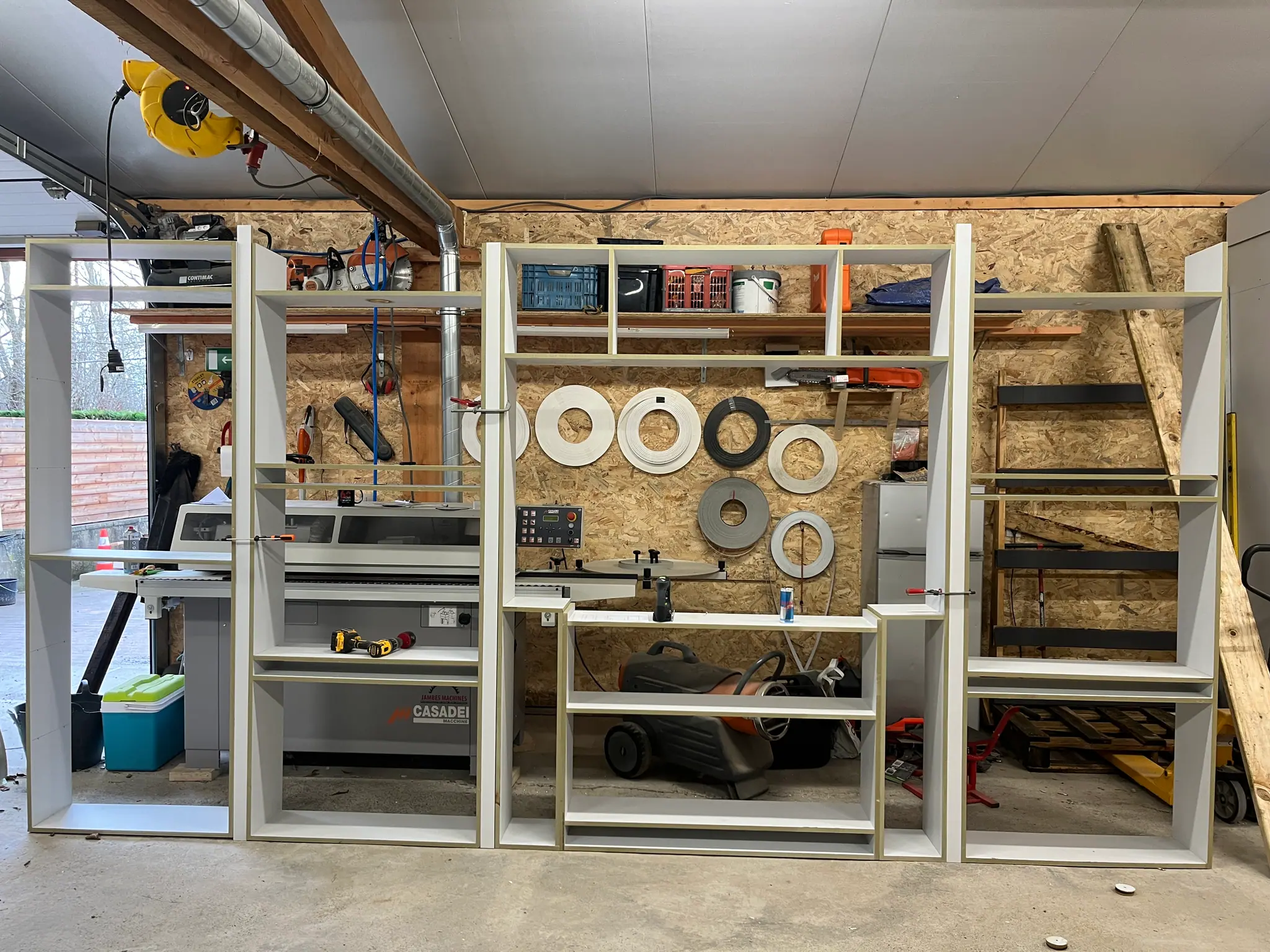 Le meuble monté à blanc à l’atelier, caissons sur tréteaux devant le mur d’outils
