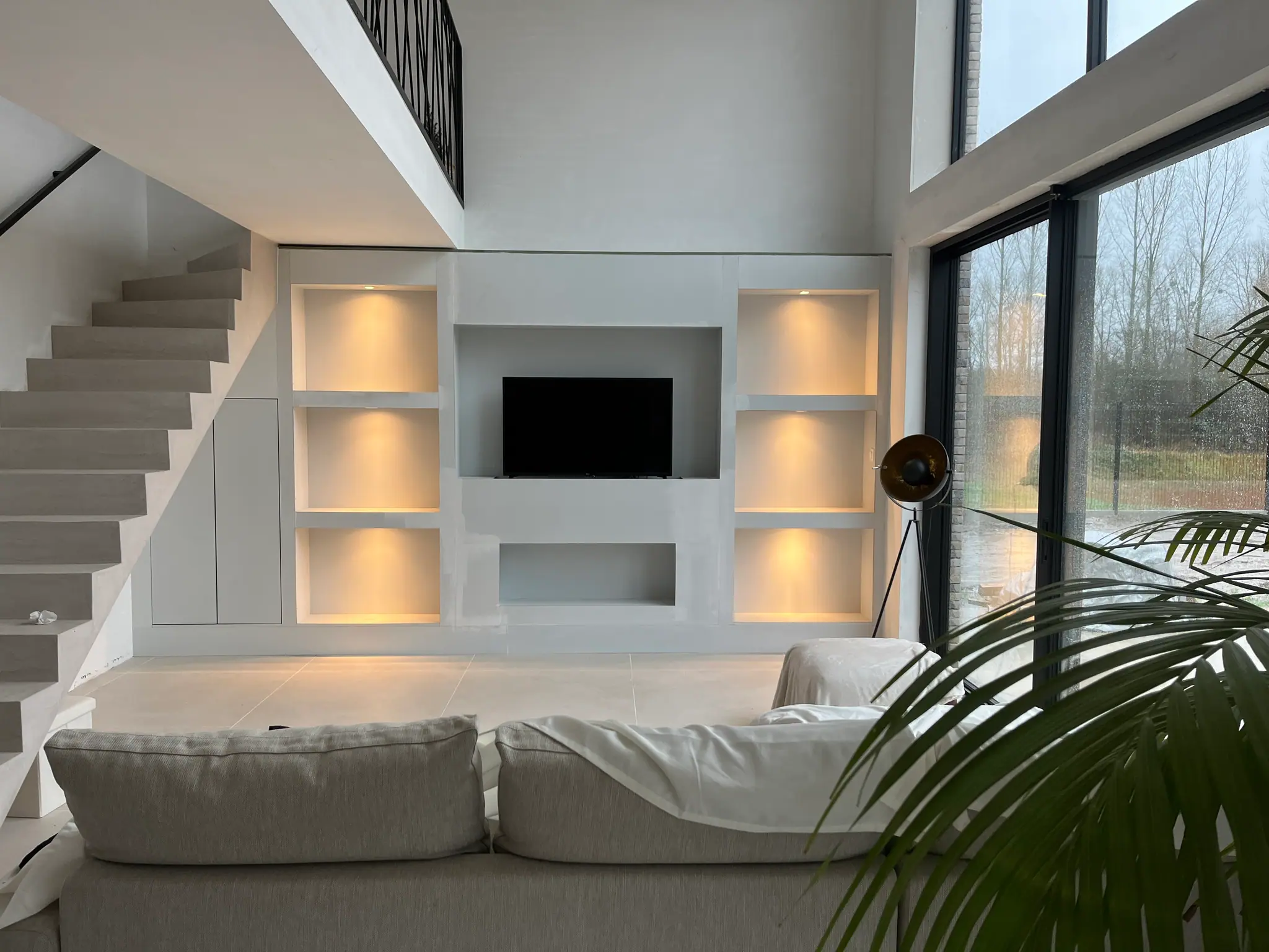 Mur de niches sur mesure rétro-éclairées dans un séjour double hauteur