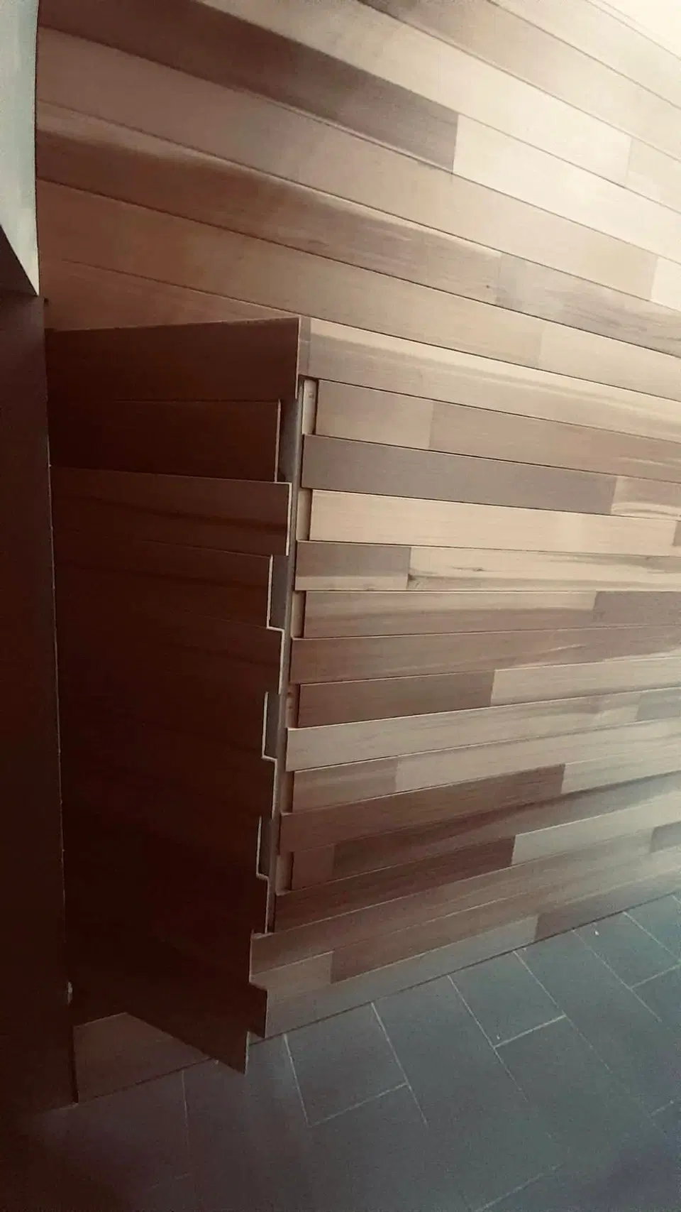 Un mur habillé de lames de largeurs et de teintes mêlées