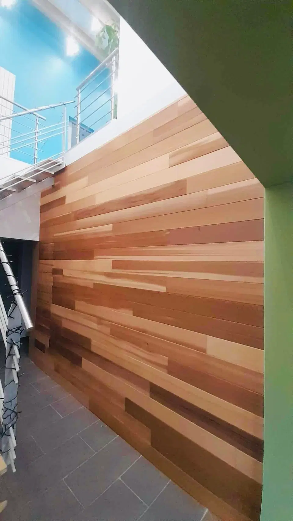 Un mur habillé de lames de largeurs et de teintes mêlées — vers la fin du chantier