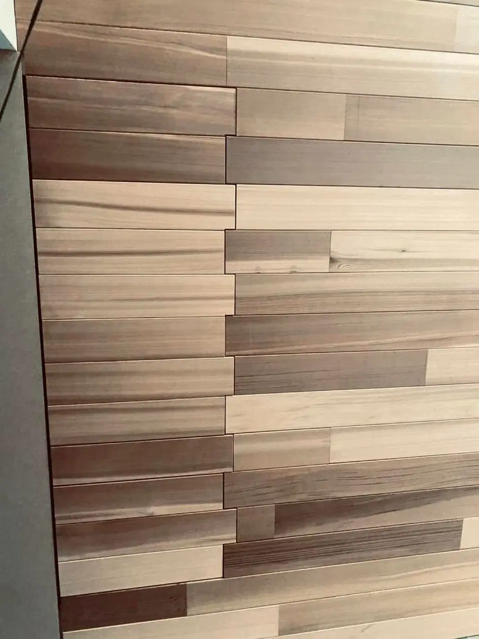 Un mur habillé de lames de largeurs et de teintes mêlées — en fin de chantier