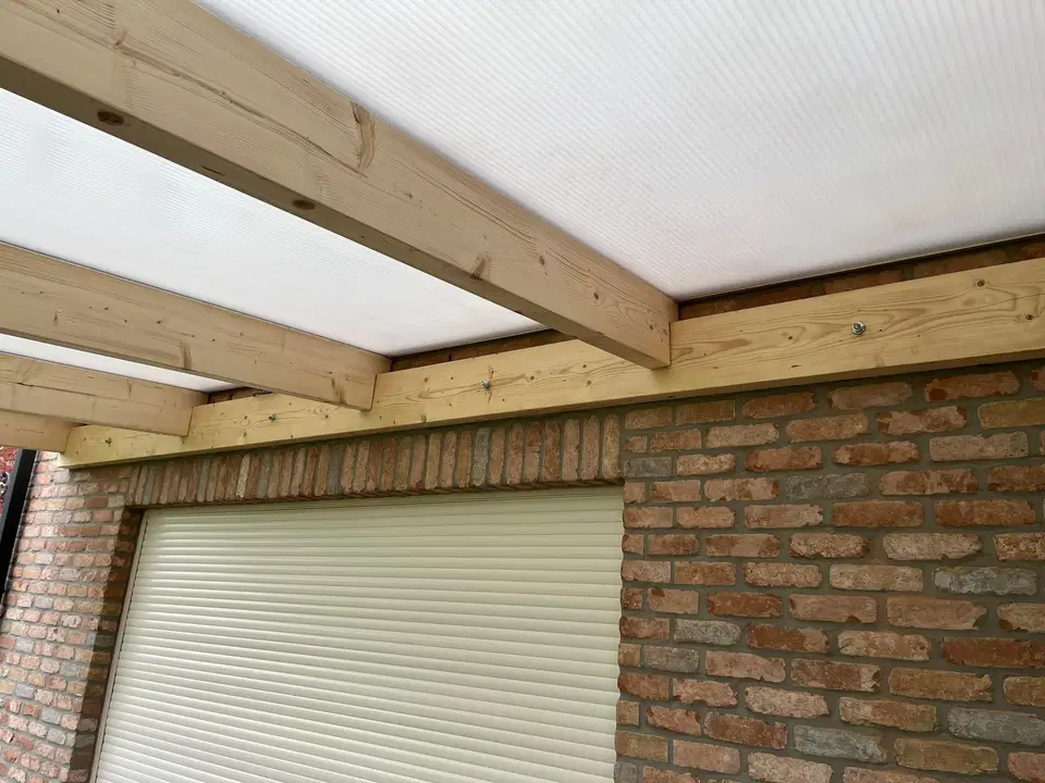 Une pergola adossée, couverture translucide — vers la fin du chantier