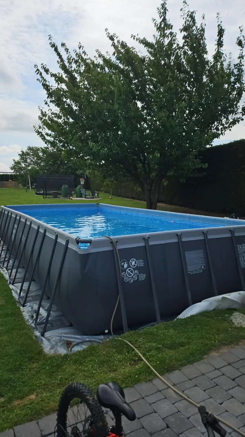 La piscine hors-sol avant travaux, parois grises apparentes, posée à même la pelouse
