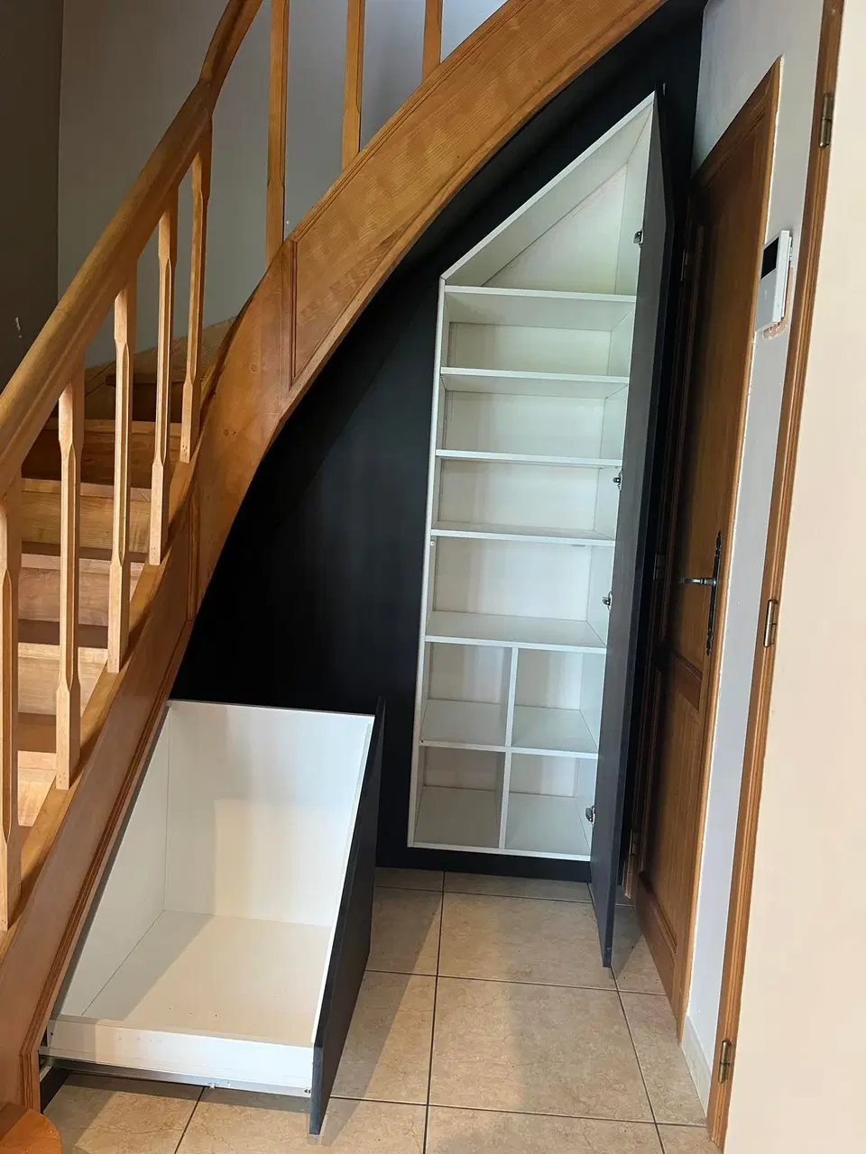 Un rangement sous escalier, portes sombres — pendant les travaux