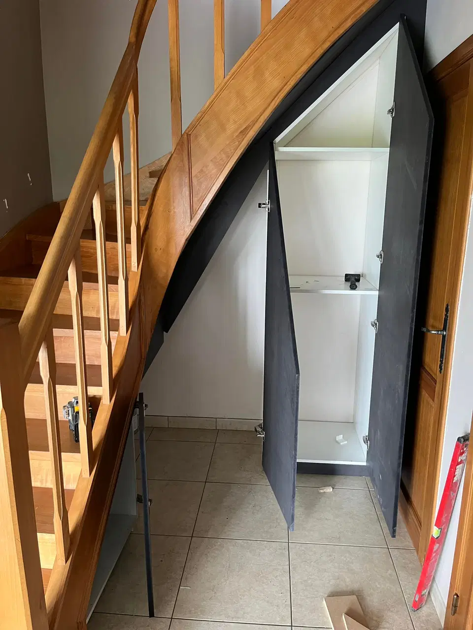 Un rangement sous escalier, portes sombres — vers la fin du chantier