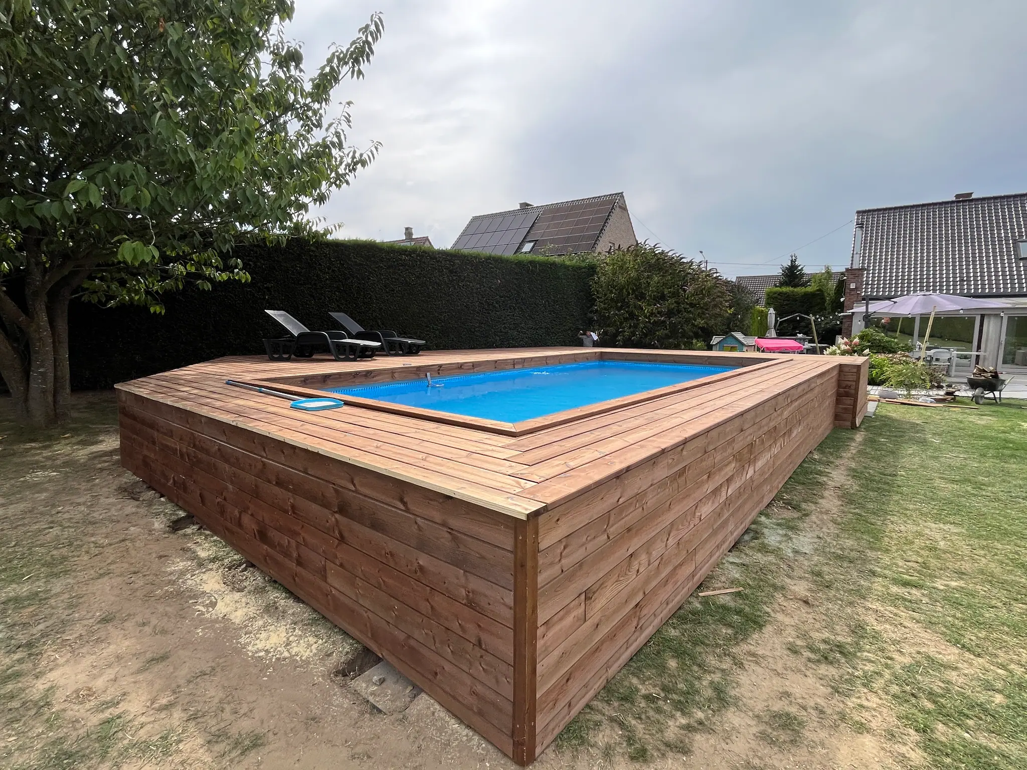 La terrasse achevée vue du jardin : la jupe de bardage ferme le pourtour et pose le volume sur la pelouse